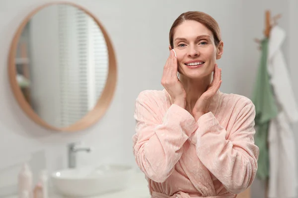 stock image Beautiful woman removing makeup with cotton pad indoors, space for text