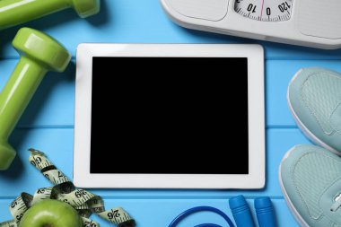 Tablet, spor ayakkabıları ve spor malzemeleri açık mavi ahşap masa, düz yatak. Kişisel eğitim