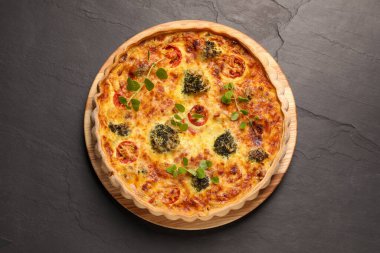 Lezzetli ev yapımı sebzeli kiş. Koyu masada, üst tarafta.