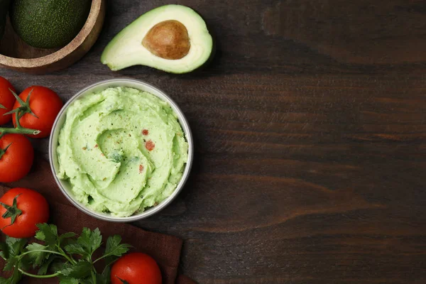 Stock image Bowl of delicious guacamole and ingredients on wooden table, flat lay. Space for text