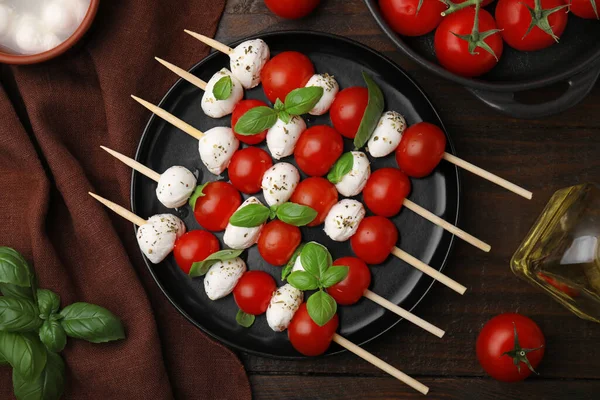 Domatesli şişler, mozzarella topları, fesleğen ve baharatlar ahşap masada, düz yatıyordu.