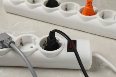 Gri mermer masa üzerinde uzatma kabloları olan güç şeridi, yakın plan. Elektrikçi ekipmanı.