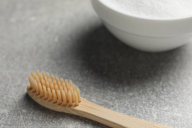 Bambu diş fırçası ve kabartma tozu gri masada, yakın plan.