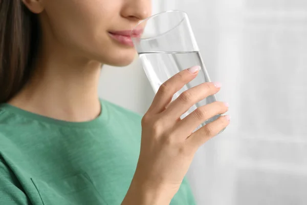 Healthy habit. Woman drinking fresh water from glass indoors, closeup