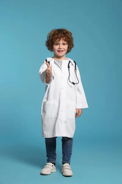 Liten Pojke Medicinsk Uniform Visar Tummen Upp Ljusblå Bakgrund — Stockfoto