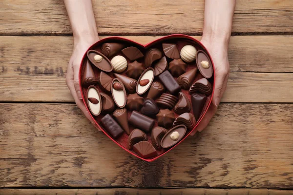 Vrouw Met Hartvormige Doos Met Heerlijke Chocolade Snoepjes Aan Houten — Stockfoto