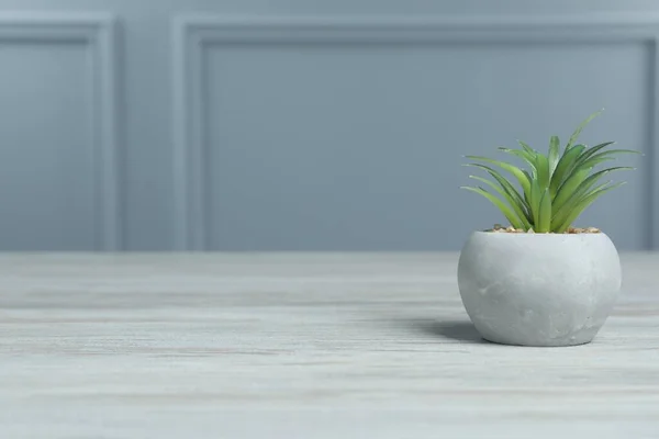 花盆中美丽的人造植物在灰墙附近的白色木制桌子上 文字空间 — 图库照片