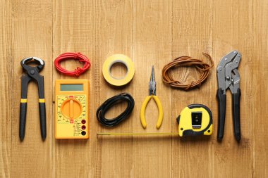 Wires and electrician's tools on wooden table, flat lay