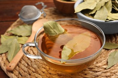 Hasır hasırın üzerinde defne yaprakları olan taze demlenmiş çay, yakın plan.