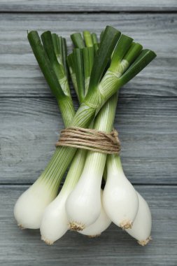 Gri ahşap masada yeşil taze soğan yığını.