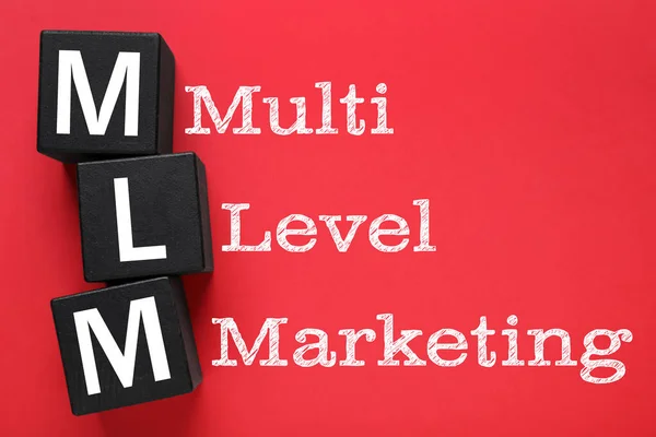 Multi-level marketing. Abbreviation MLM of cubes with letters on red background, top view