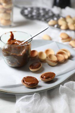 Tabağında konsantre süt olan lezzetli ceviz şekilli kurabiyeler, yakın plan.