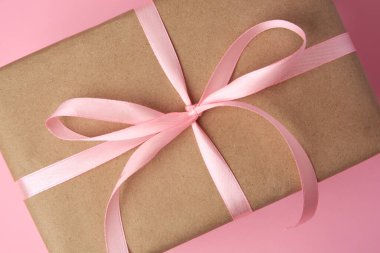 Pembe arka planda fiyonklu güzel hediye kutusu, üst manzara