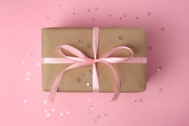 Pembe arka planda fiyonklu ve konfetili güzel bir hediye kutusu.