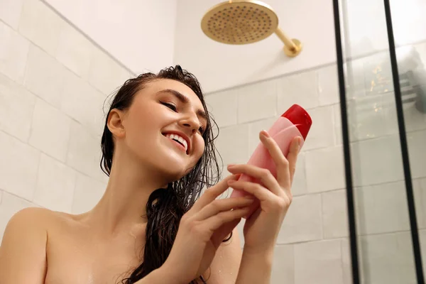 快乐的女人带着一瓶洗发水在家里洗澡 视角低 — 图库照片