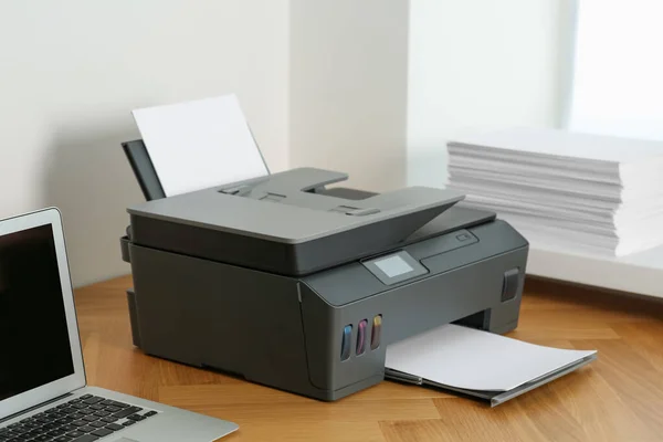 办公室的木制桌子上装有纸张和笔记本电脑的现代打印机 — 图库照片