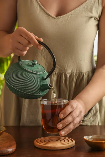 Woman Pouring Freshly Brewed Tea Teapot Cup Wooden Table Closeup — Stock Photo, Image