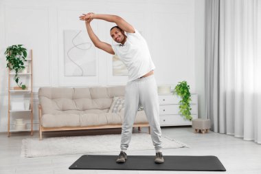 Adam evde spor paspası üzerinde sabah egzersizi yapıyor.