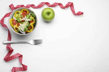 Ölçüm bandı, salata, elma ve çatal, beyaz arka plan, düz yatak. Metin için boşluk