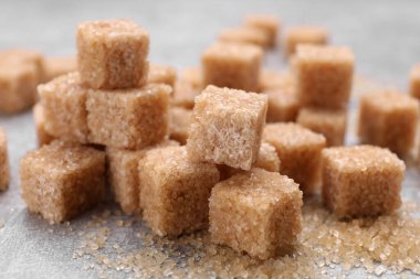 Gri masada bir sürü kahverengi şeker küpü, yakın plan.