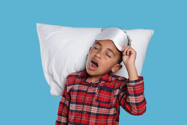 薄い青の背景に枕と睡眠マスクの少年 不眠症の問題 — ストック写真