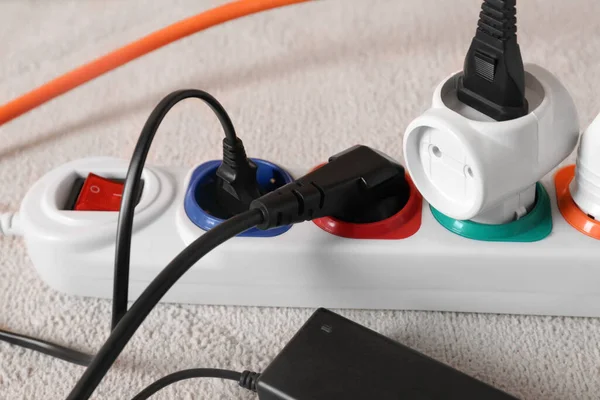 Extension cord with electrical plugs on white carpet, closeup
