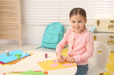 Odada masadaki yapıştırıcıyı kullanan tatlı küçük kız. Ev işyeri