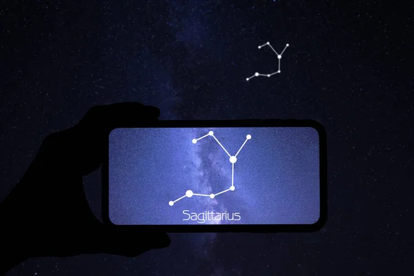 夜中に携帯電話の星の見えるアプリを使ってる男だ デバイス画面上の射手座 星座の識別棒図パターン — ストック写真