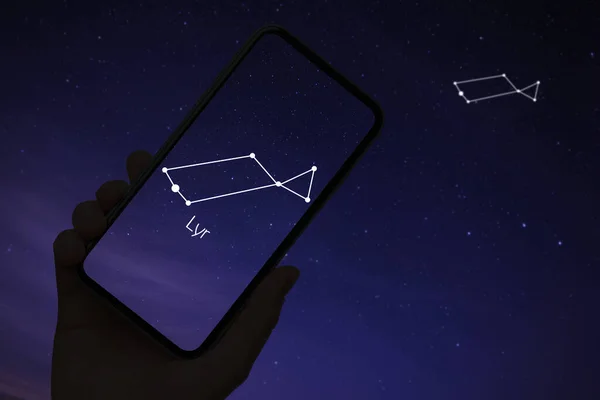 stock image Woman using stargazing app on her phone at night, closeup. Identified stick figure pattern of Lyra constellation on device screen