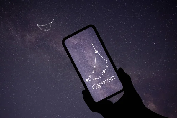 夜中に携帯電話の星の見えるアプリを使ってる男だ デバイス画面上のCapricornus Capricorn 星座の識別棒図パターン — ストック写真