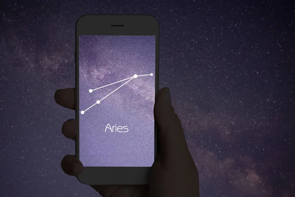 Woman using stargazing app on her phone at night, closeup. Identified stick figure pattern of Aries constellation on device screen