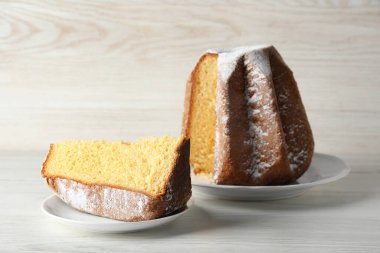 Delicious Pandoro cake decorated with powdered sugar on white wooden table. Traditional Italian pastry
