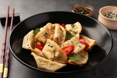 Lezzetli Gyoza (Asyalı börekler) kasede ve yemek çubukları gri masada, yakın plan