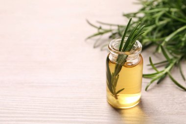 Bir şişe yağ ve beyaz ahşap masada taze biberiye, yakın plan. Metin için boşluk