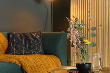 Güzel çiçekleri ve yeşil dalları olan şık ikebana evinde rahat bir atmosfer taşıyor.