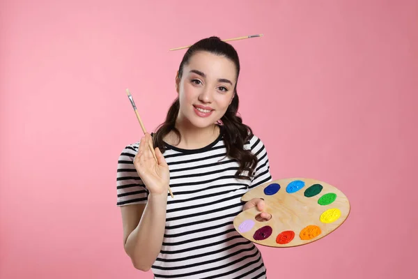 带着粉红背景的绘画工具的女人年轻的艺术家 — 图库照片