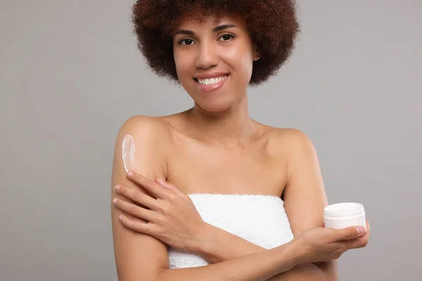 Mooie Jonge Vrouw Aanbrengen Lichaam Crème Arm Grijze Achtergrond — Stockfoto