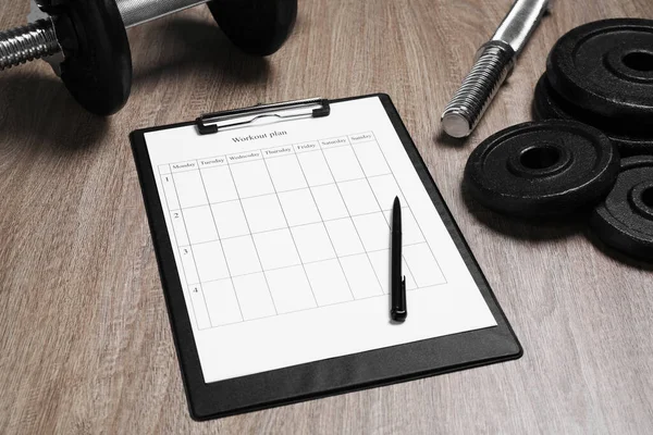 Workout plan, pen and sports equipment on wooden table. Personal training