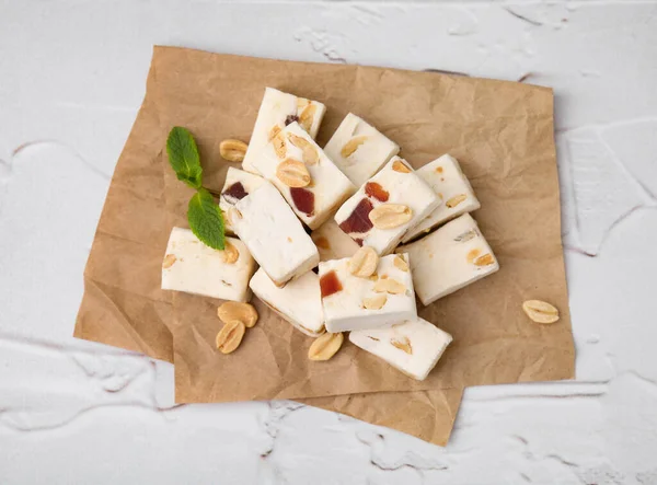 stock image Pieces of delicious nutty nougat on white textured table, top view