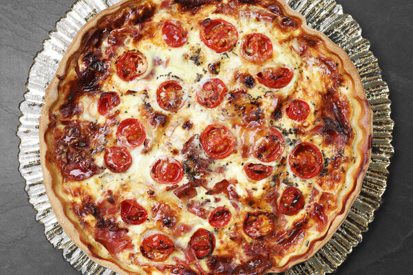 Delicious homemade quiche with prosciutto and tomatoes on table, top view