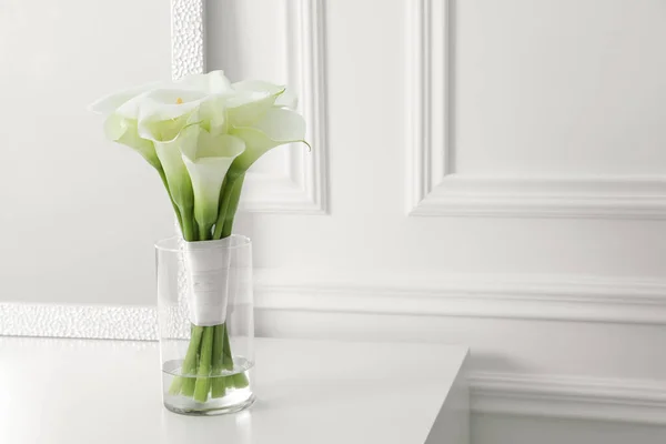 美丽的油菜百合花 白色桌子上的玻璃瓶系有彩带 文字的空间 — 图库照片