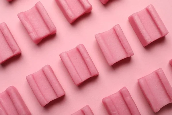 Tasty chewing gums on pink background, flat lay