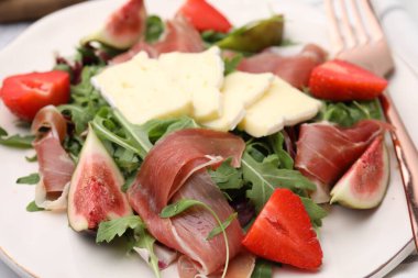 Peynirli lezzetli salata, prosciutto, çilek ve beyaz tabakta incir, yakın plan.