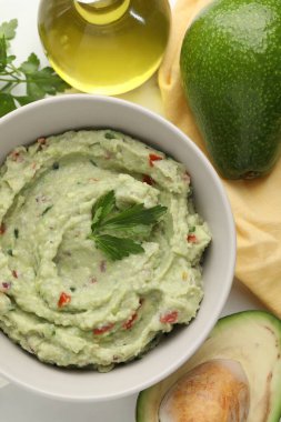 Lezzetli guacamole ve malzemeler beyaz masada, düz yerde.