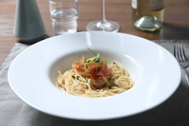 Prosciutto ve mikroyeşillikli lezzetli spagetti ahşap masada servis edilir, yakın plan. Makarna yemeğinin enfes sunumu