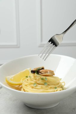 Açık gri masada midyeli ve limonlu capellini yemek, yakın plan. Makarna yemeğinin enfes sunumu