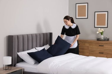 Otel odasında yatak yapma genç Oda hizmetçisi