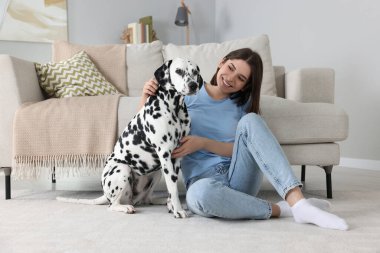 Evinde sevimli Dalmaçyalı köpeği olan mutlu genç bir kadın. Sevimli hayvan