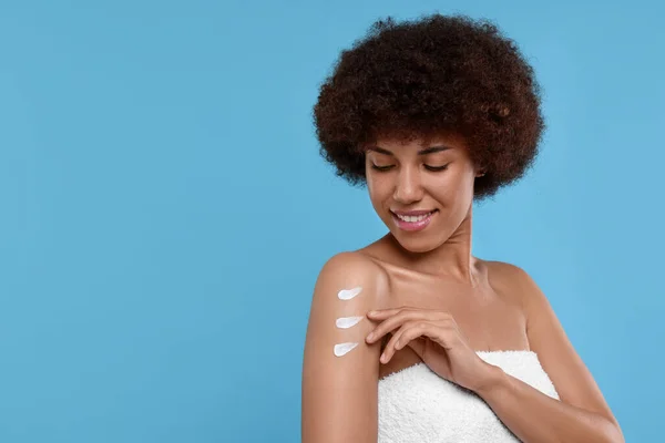 Mooie Jonge Vrouw Aanbrengen Lichaam Crème Arm Lichtblauwe Achtergrond Ruimte — Stockfoto