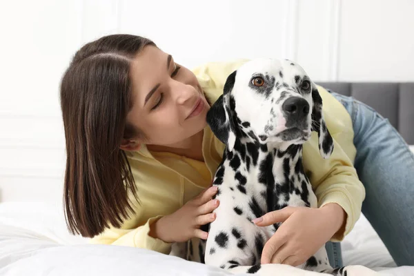 漂亮的女人和她可爱的达尔马提亚犬躺在床上可爱的宠物 — 图库照片
